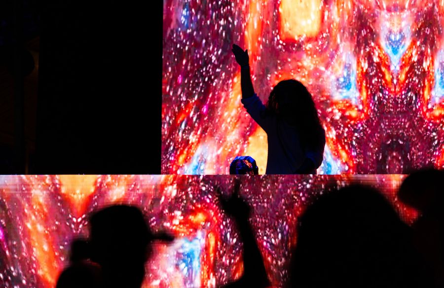 A performer raising an arm above a crowd at night