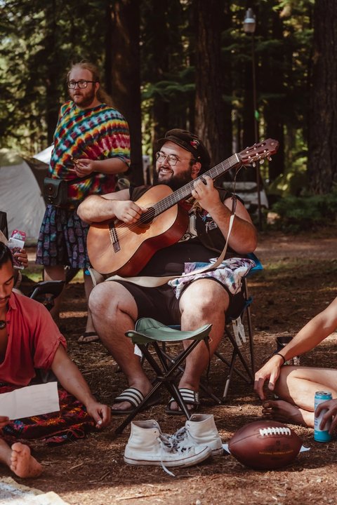 Acoustic musicians playing together beneath the trees