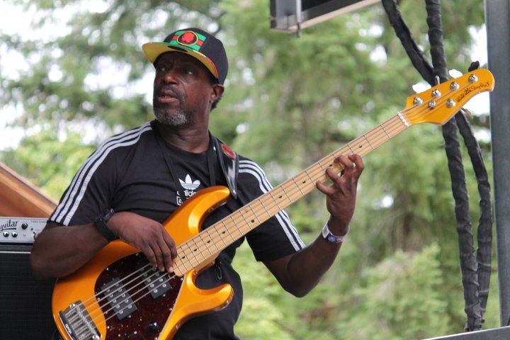 Bassist playing an orange bass guitar outdoors