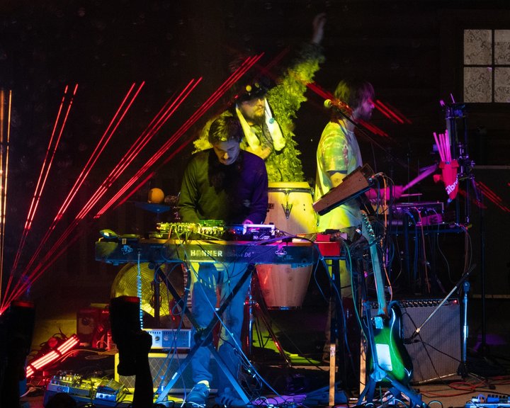 Keyboard player performing beneath red laser beams