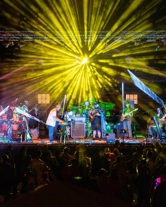 Live band beneath a burst of yellow stage lights
