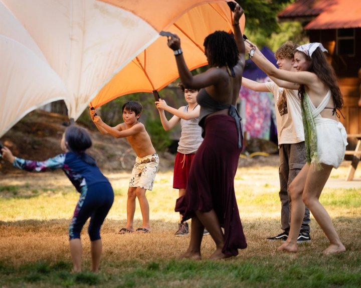 Adults and children dancing beneath a fabric canopy