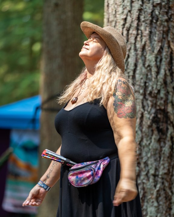 Festival attendee dancing beside an evergreen tree