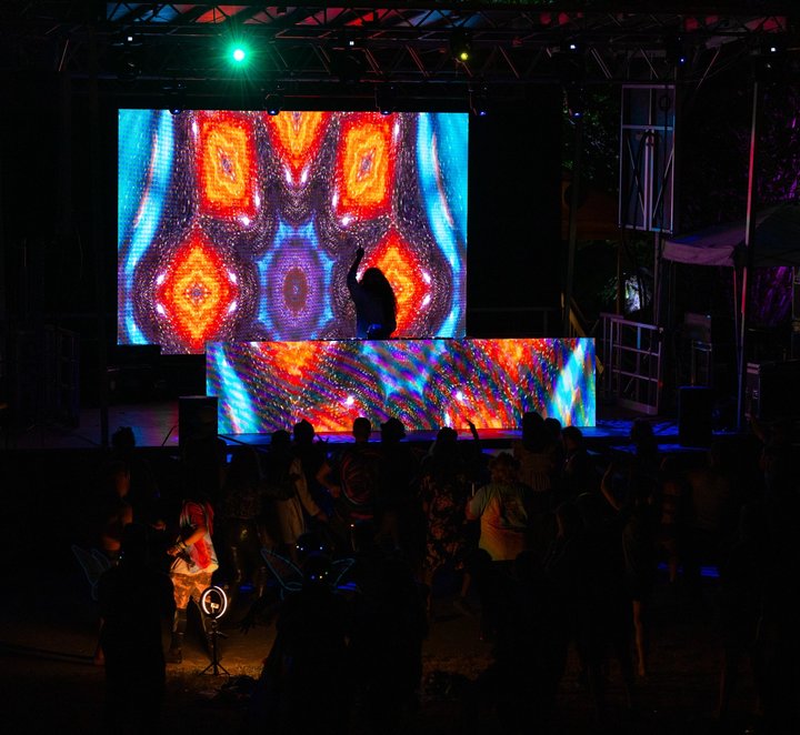 DJ stage displaying bright kaleidoscopic visual patterns