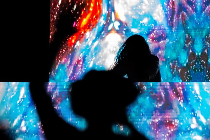 DJ and audience silhouetted against colorful stage visuals