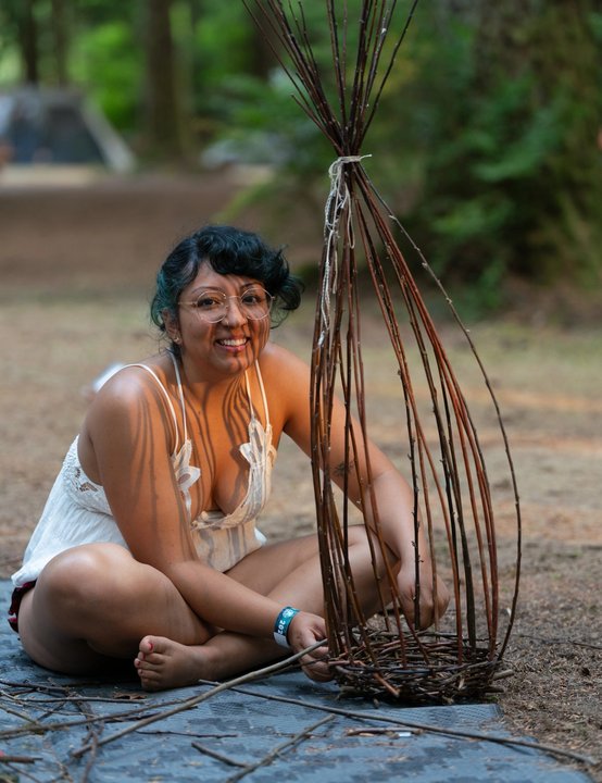 Festival attendee working on a woven branch sculpture